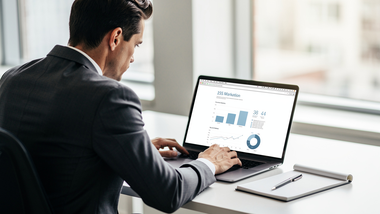 Diretor de negócios revisando relatório de marketing simples e organizado em laptop no escritório
