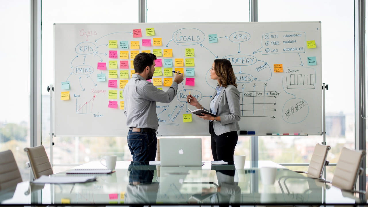 Dois profissionais discutindo estratégia empresarial em quadro branco com post-its coloridos em sala iluminada